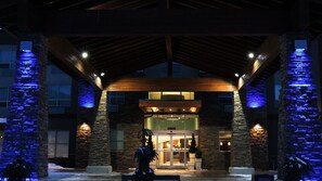 A building entrance with a stone facade, wooden beams, and illuminated blue lights. - Holiday Inn Express Golden-Kicking Horse by IHG (Golden)