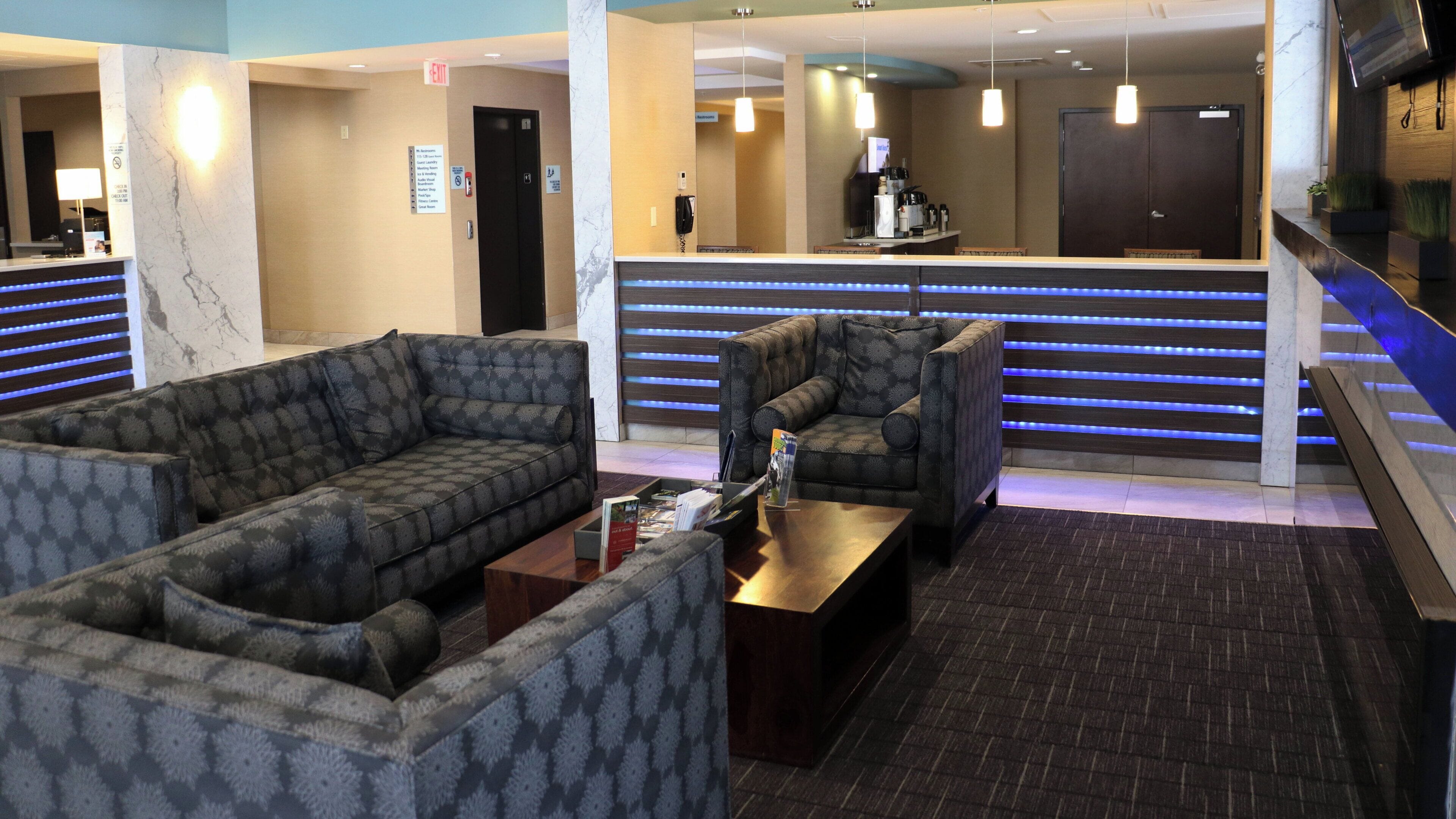 A hotel lobby with seating areas, a reception desk, and a staircase.