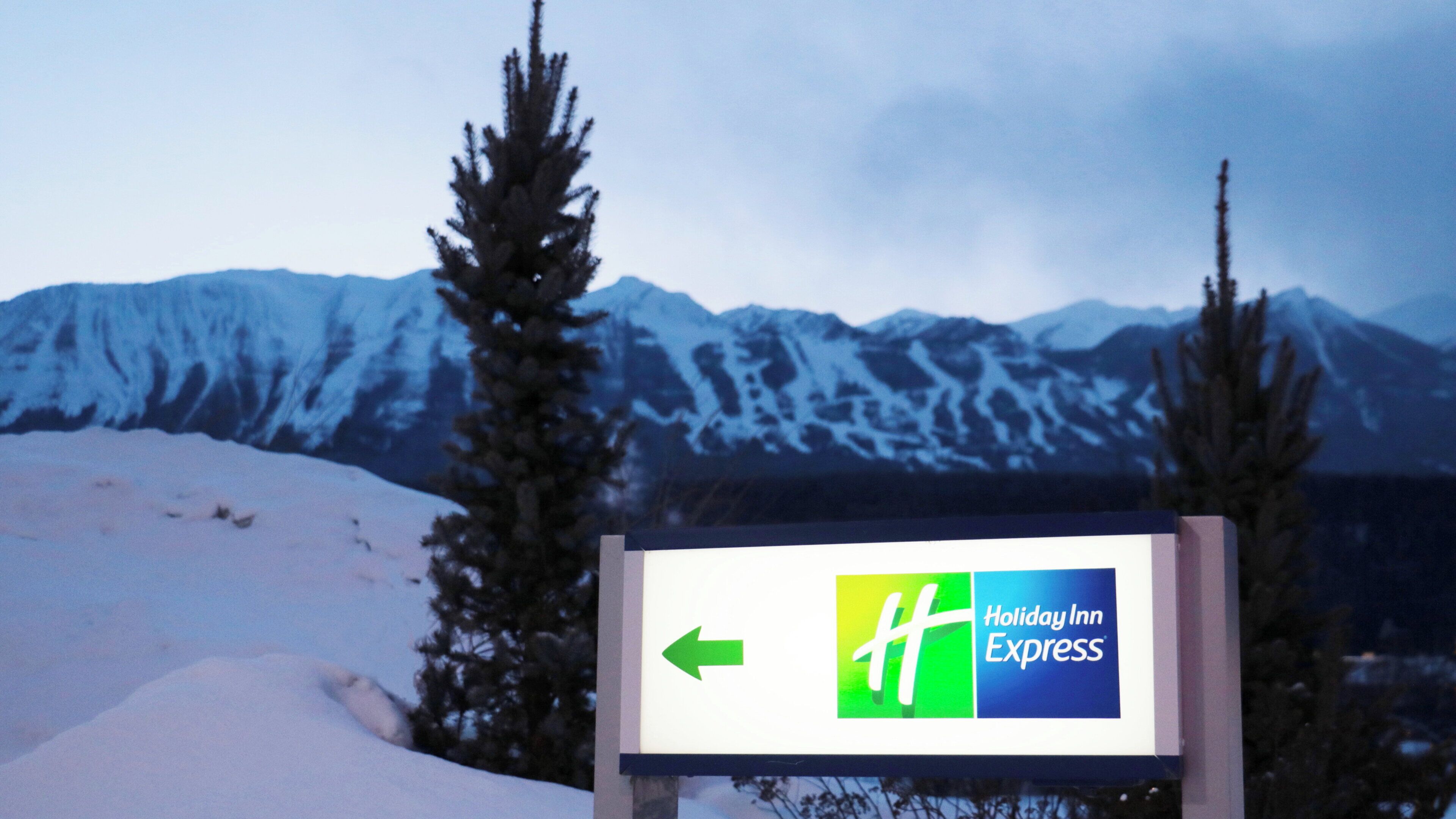 A sign with a green arrow pointing left, indicating the direction to Holiday Inn Express.