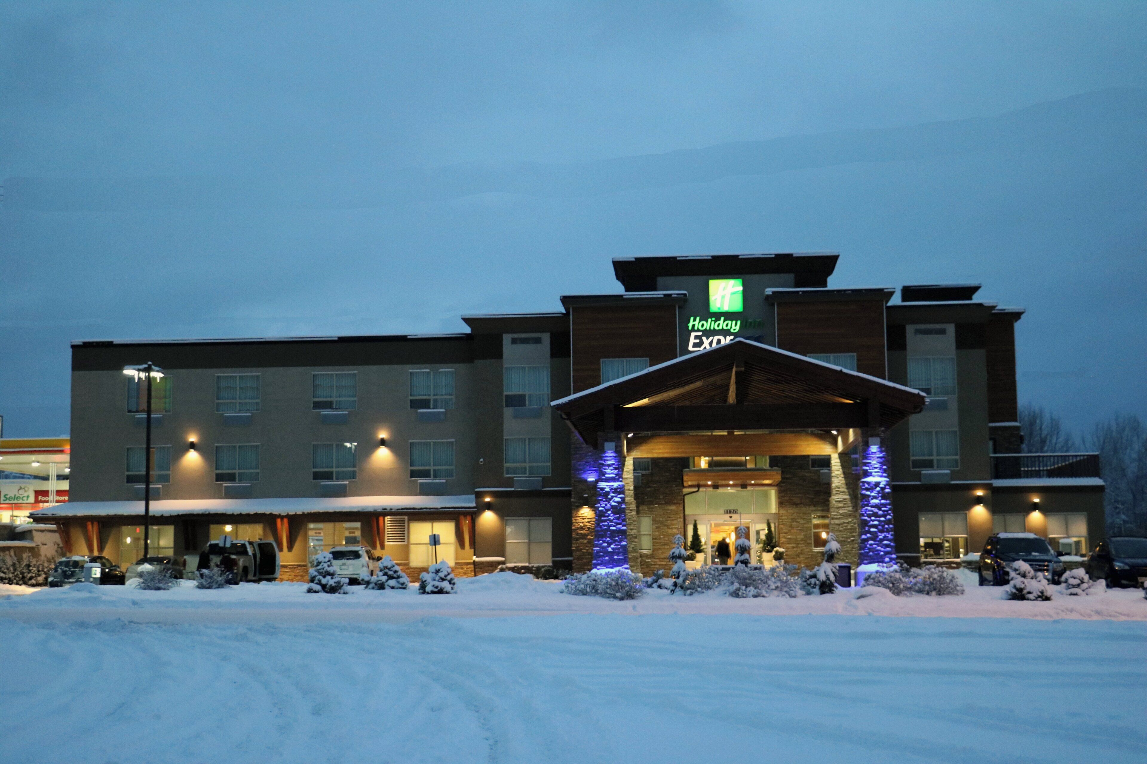 Een Holiday Inn Express hotel met een overdekte ingang, een parkeerplaats bedekt met sneeuw, en meerdere verdiepingen.
