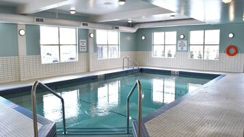 Une piscine intérieure à l’eau claire, avec des murs carrelés et des fenêtres.