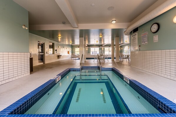 A swimming pool with clear water, tiled walls, and a clock on the wall. - Holiday Inn Express Golden-Kicking Horse by IHG (Golden)