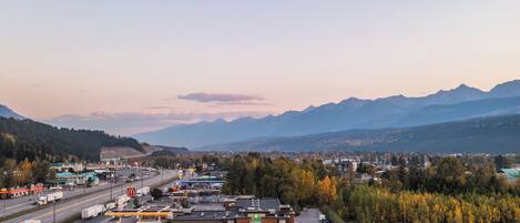 A hotel with a parking lot, a gas station, and a view of mountains.