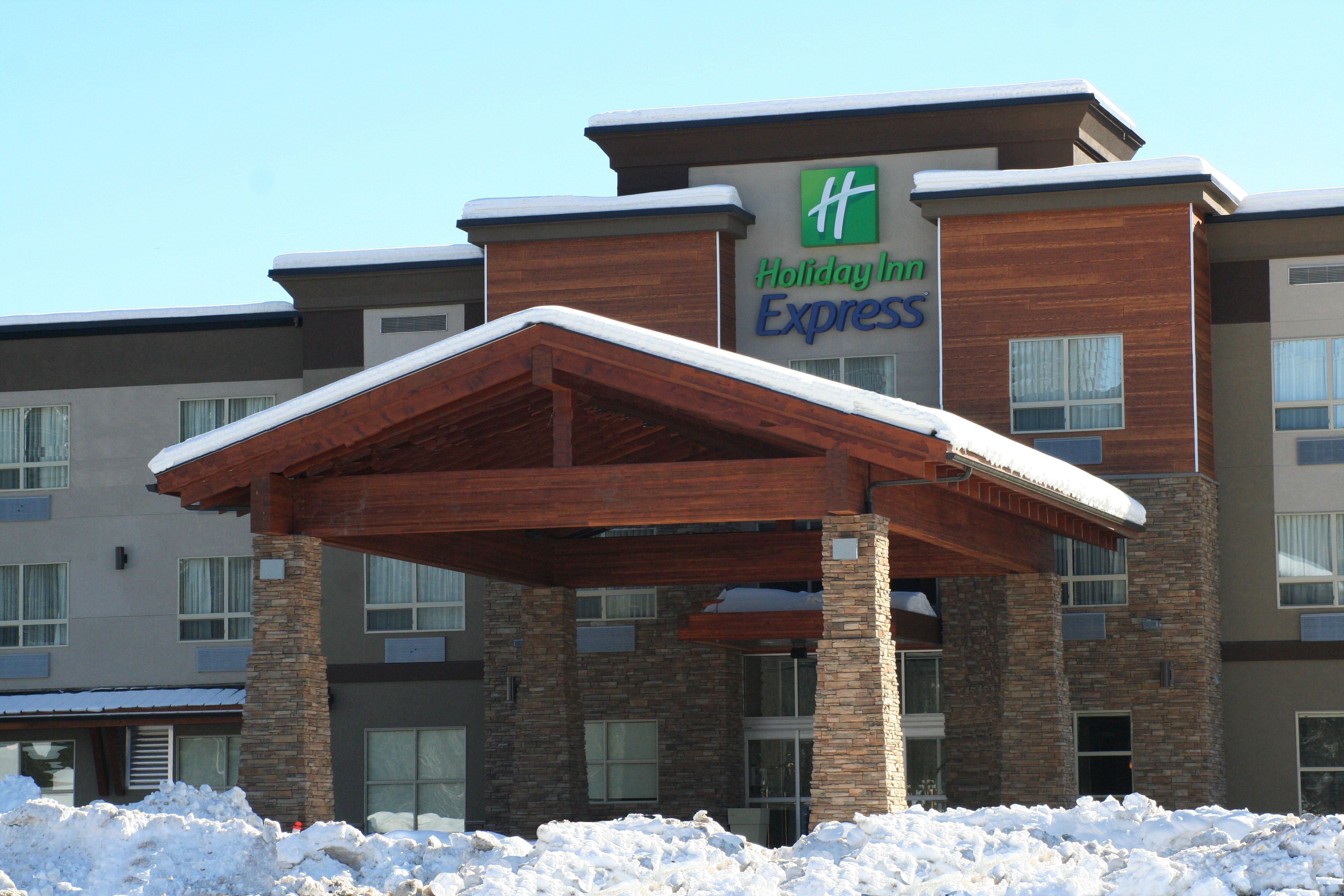 A Holiday Inn Express building with a covered entrance and snow on the roof.
