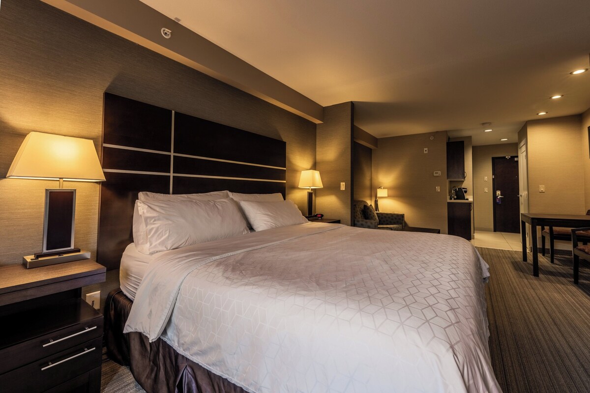 A hotel room with a large bed, bedside lamps, a desk, and a chair.