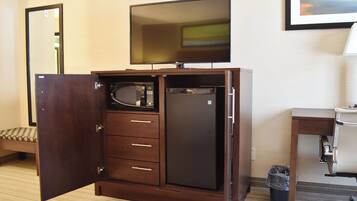 A compact room with a wardrobe, a microwave, and a refrigerator.