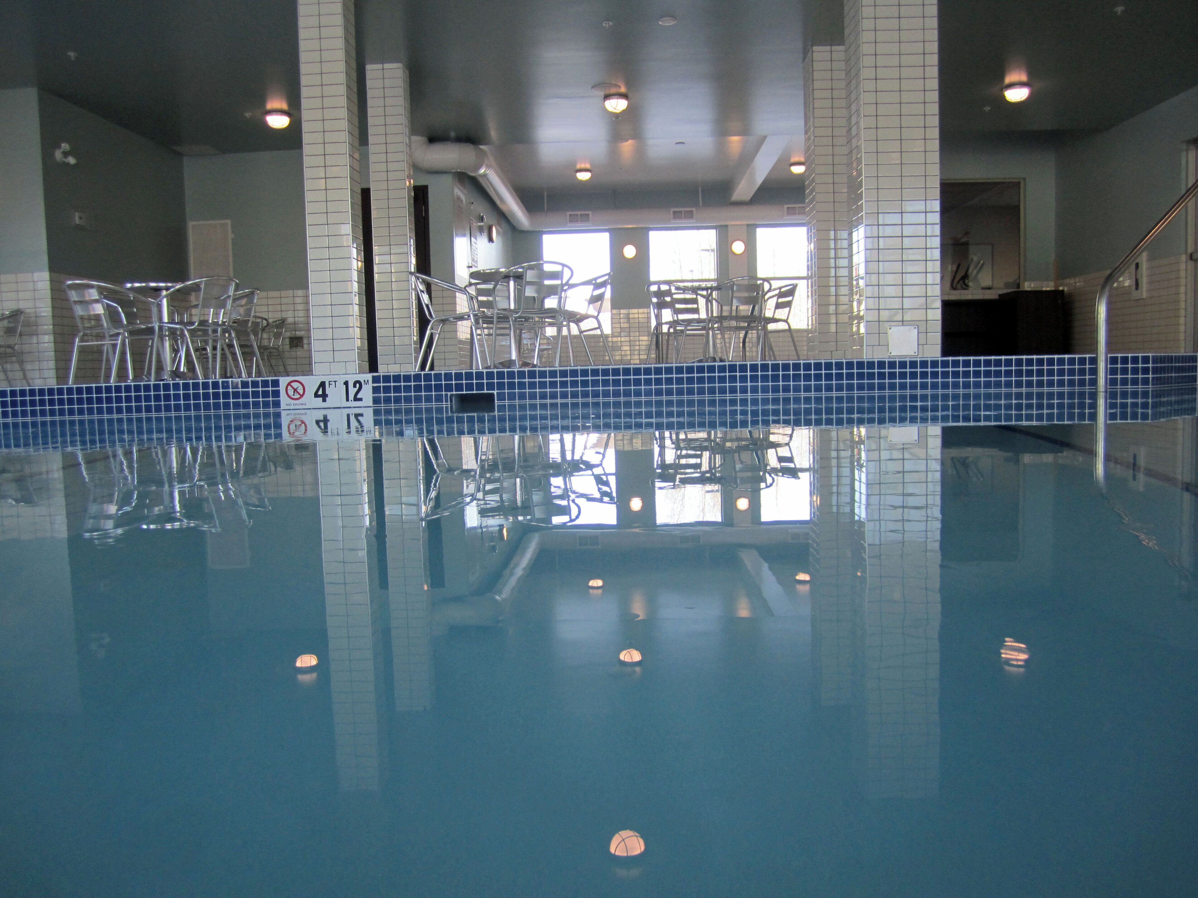 An indoor swimming pool with clear water, tiled walls, and a blue safety lane.