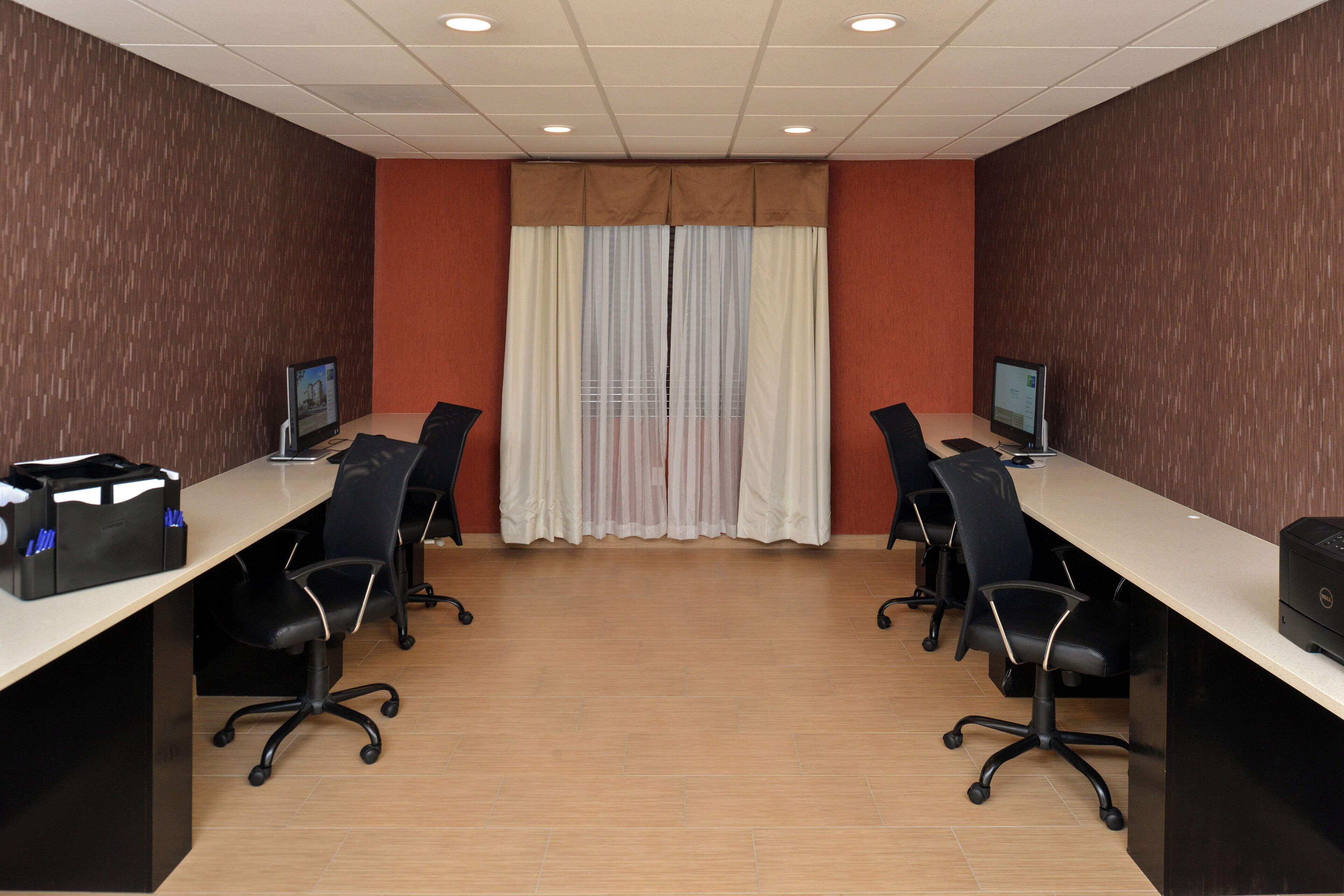 Sala de conferência com duas mesas, cadeiras e computadores.