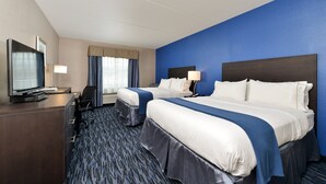 Une chambre d’hôtel avec deux lits, un bureau avec une télévision et une fenêtre avec des rideaux.