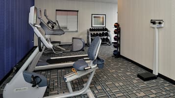 Un gimnasio con cintas de correr, una bicicleta estática y un banco para pesas.