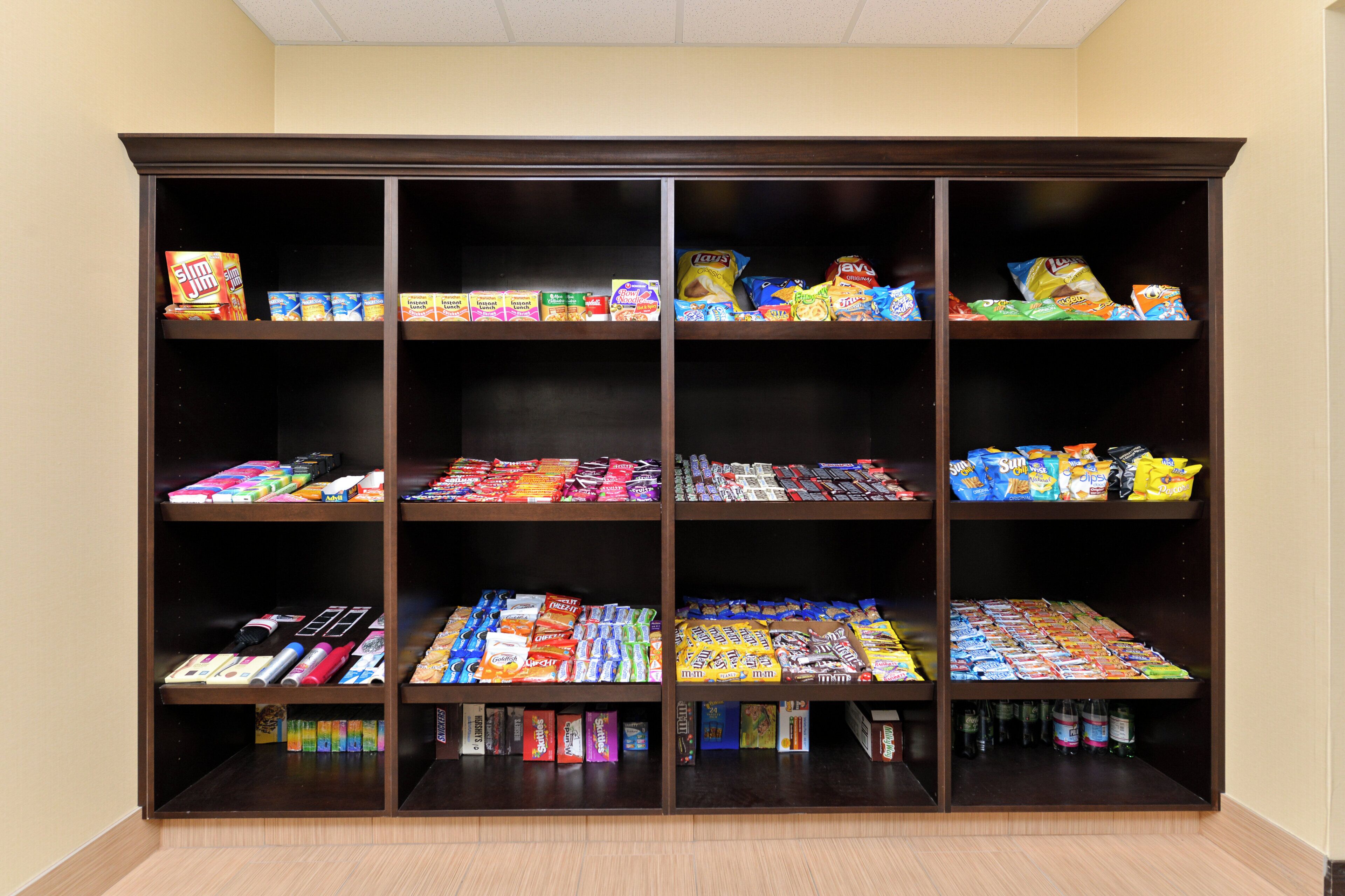 A large, dark-colored shelving unit with multiple shelves stocked with various snacks, candies, and small packaged goods.