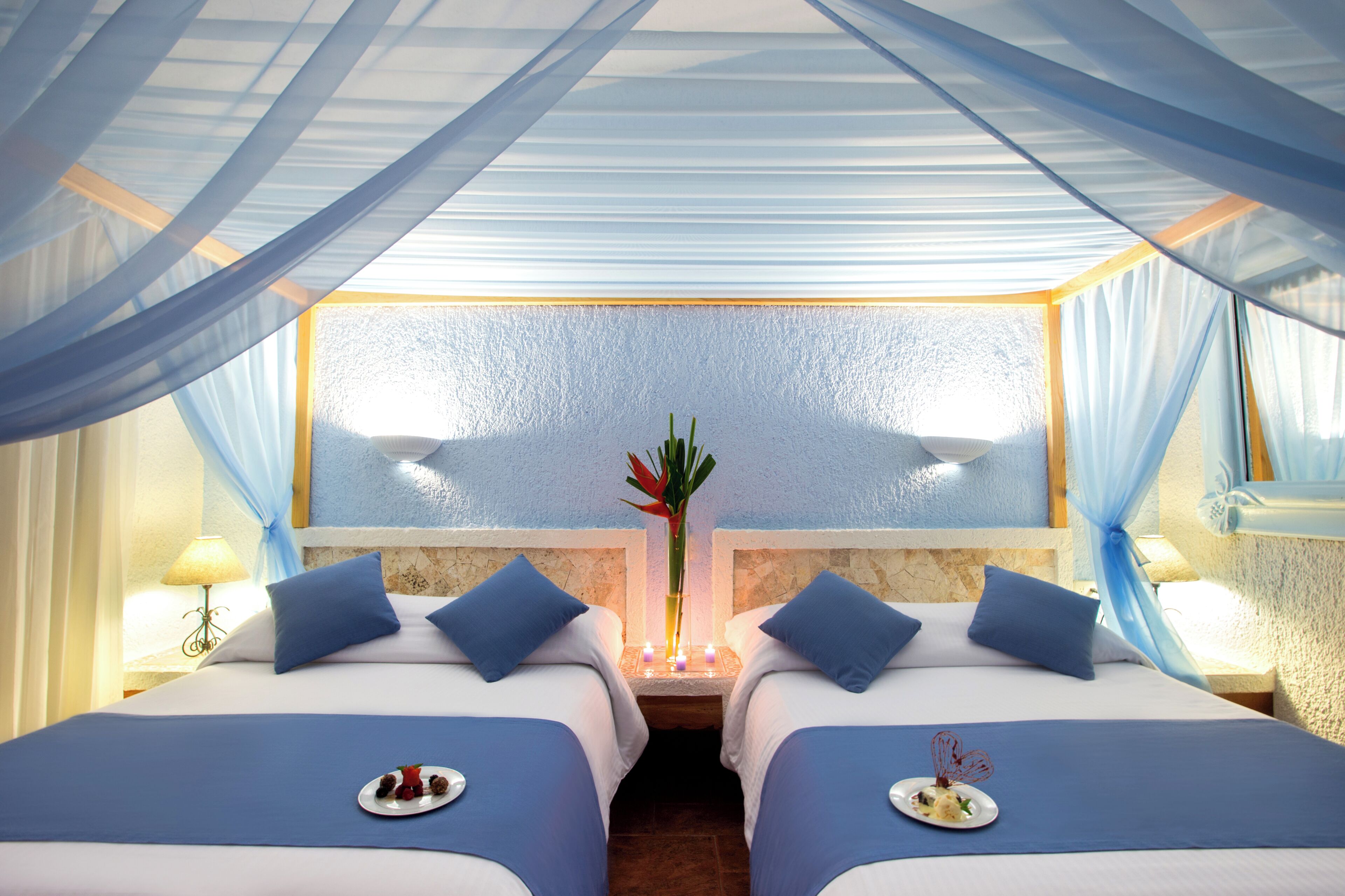 A hotel room with two beds, a large window, and a decorative centerpiece.