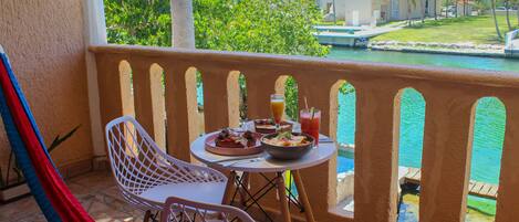 A balcony with a table set for dining, chairs, and a hammock.