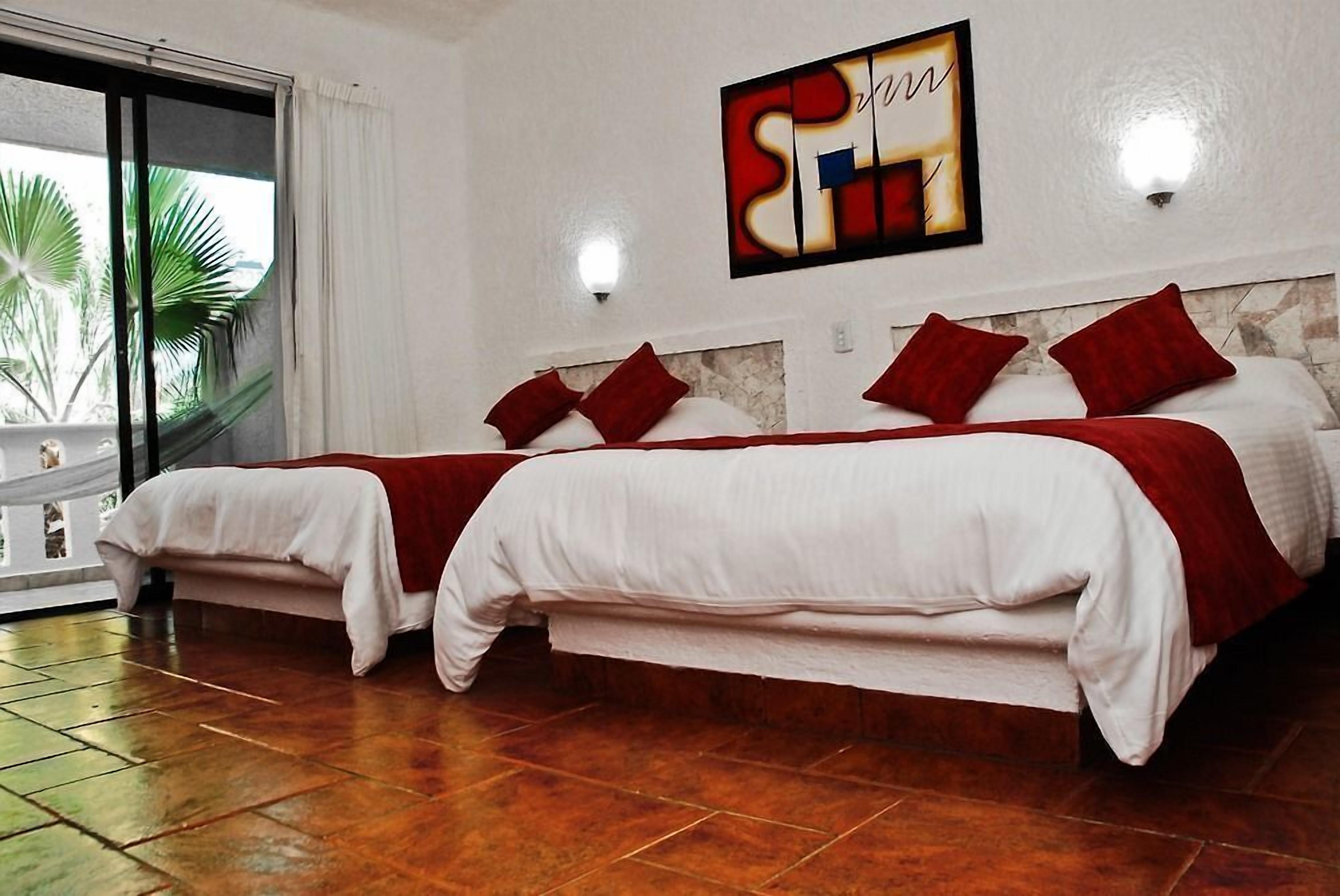 A hotel room with two beds, a large window with a view of palm trees, and a wall-mounted artwork.