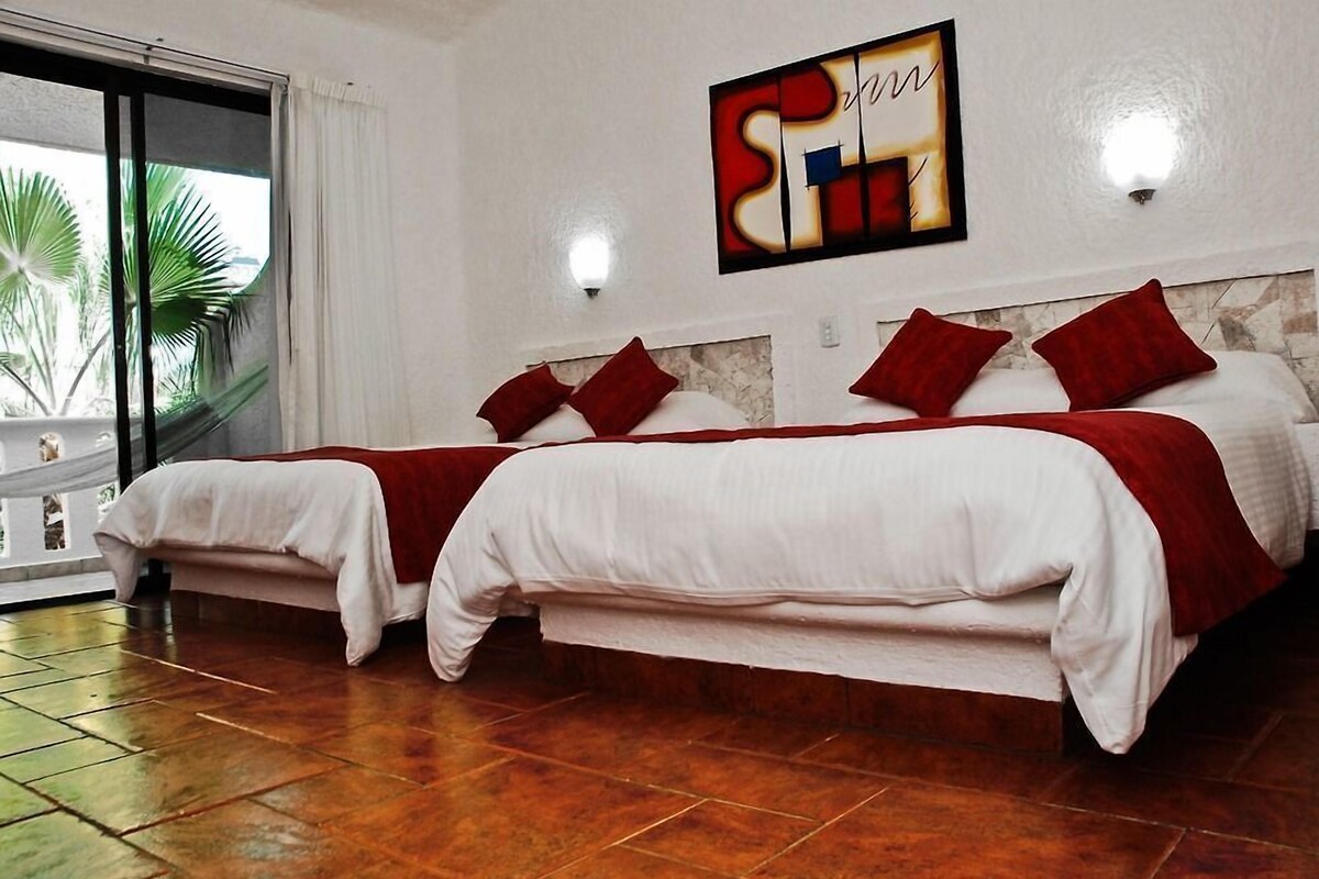 A hotel room with two beds, a large window with a view of palm trees, and a wall-mounted artwork.