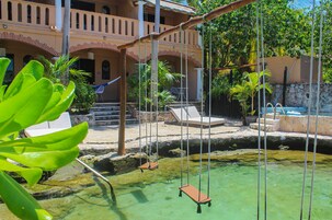 A pool area with a swing set, lounge chairs, and a stone wall.