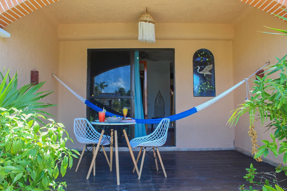 A patio with a table and chairs, a hammock, and a door leading to the interior.