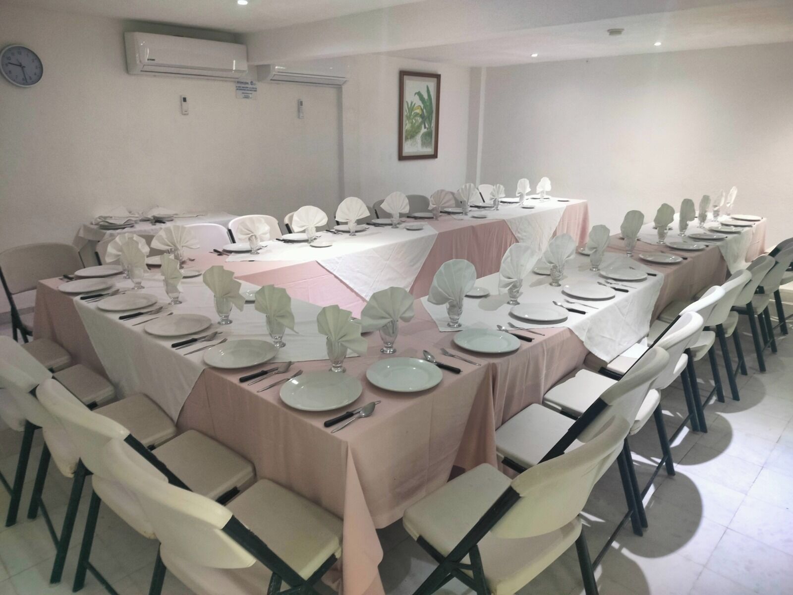 A conference room with a long table set for a meeting, surrounded by chairs.