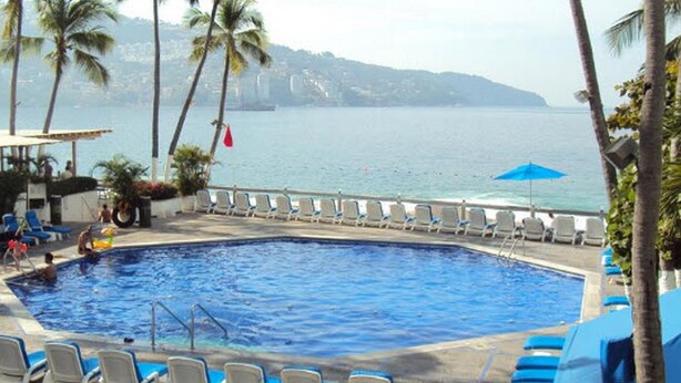 A swimming pool with lounge chairs and a view of the sea. - Hotel Acapulco Malibu (Acapulco)