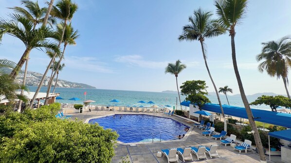 A pool area with lounge chairs and umbrellas, overlooking a body of water. - Hotel Acapulco Malibu (Acapulco)