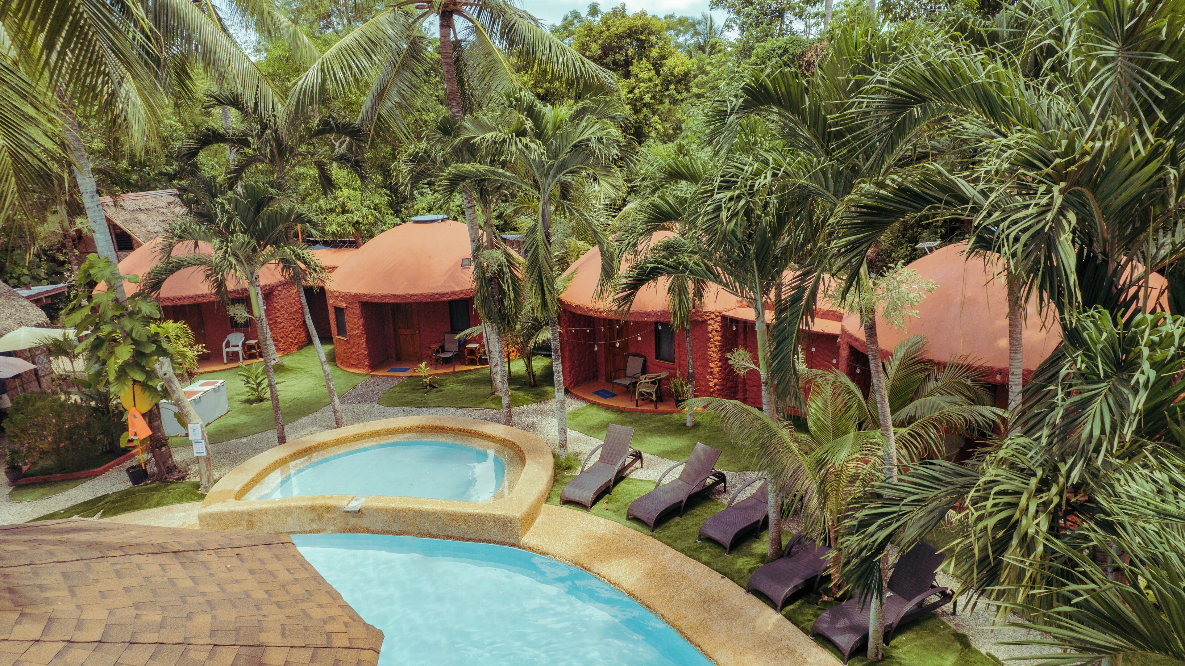 Un resort con piscina, palmeras y alojamientos tipo bungalow.