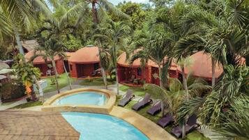 Un resort con piscina, palmeras y alojamientos tipo bungalow.