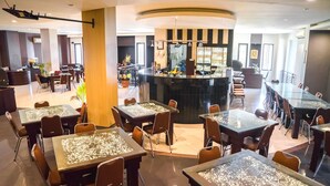 Een hotel lobby met meerdere eettafels, een bar in het midden en een receptiebalie.