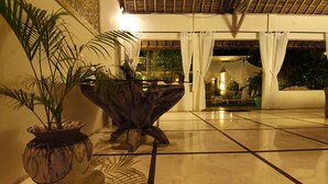 Un vestíbul ampli amb terra de rajola, una gran jardiniera decorativa i una taula de fusta única.