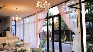 Recepció d'hotel amb zona de seients, un penjallum i grans finestres amb cortines.