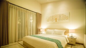 Habitació d'hotel amb un llit gran, una nitze amb una làmpada i una obra d'art penjada a la paret que representa un arbre.