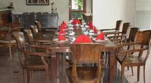 A dining area with a rectangular table set for a meal, surrounded by wooden chairs. - Nikki (DENPASAR)