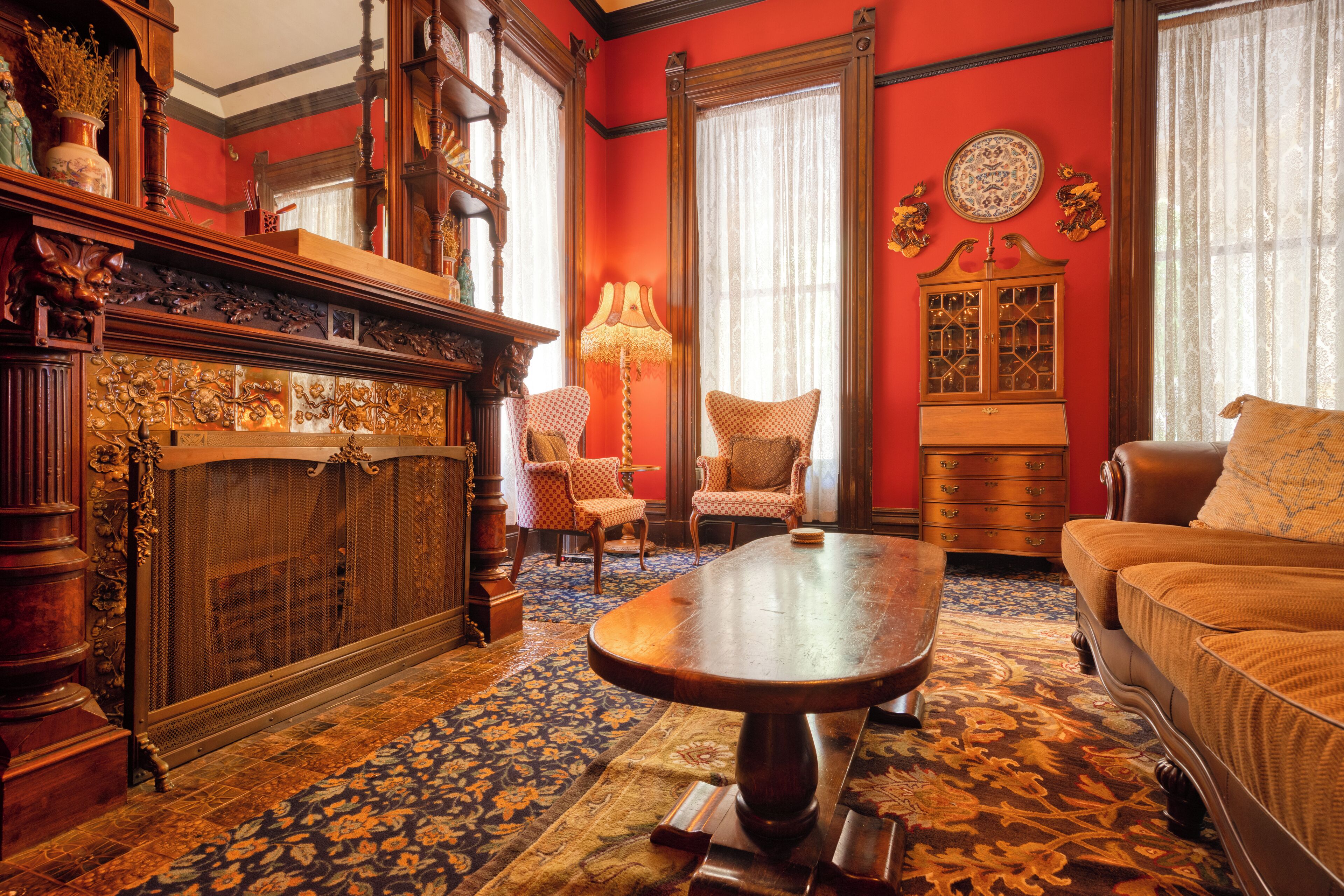 Une pièce comprenant une grande table en bois, deux fauteuils rembourrés, un canapé, une commode et un tapis à motifs.