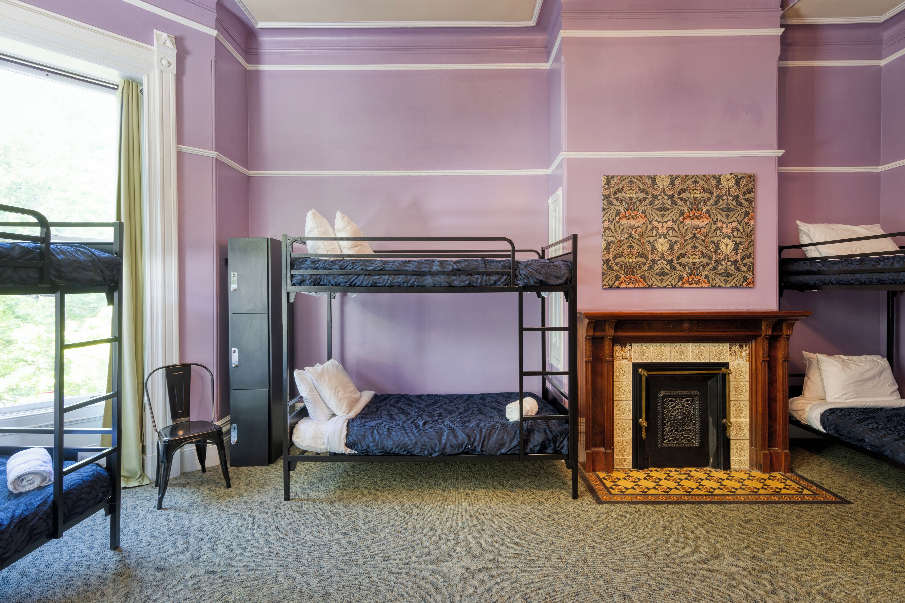 A room with bunk beds, a fireplace, and a patterned wall hanging.