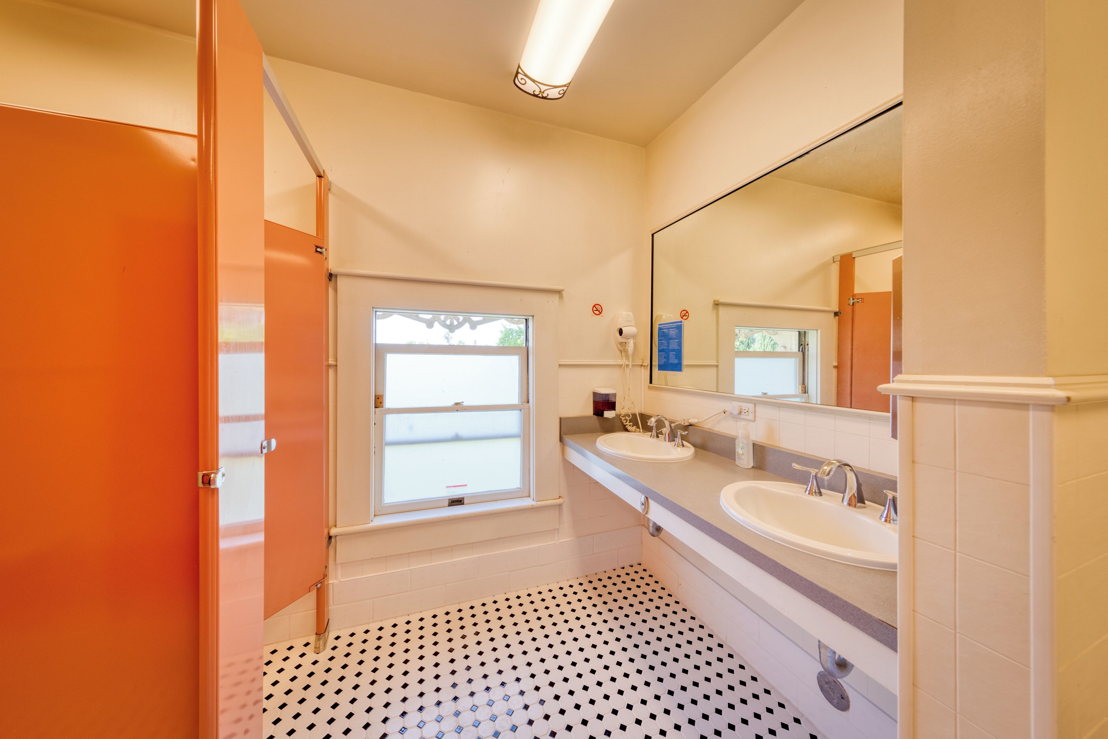 A bathroom with two sinks, a large mirror, and a patterned floor.