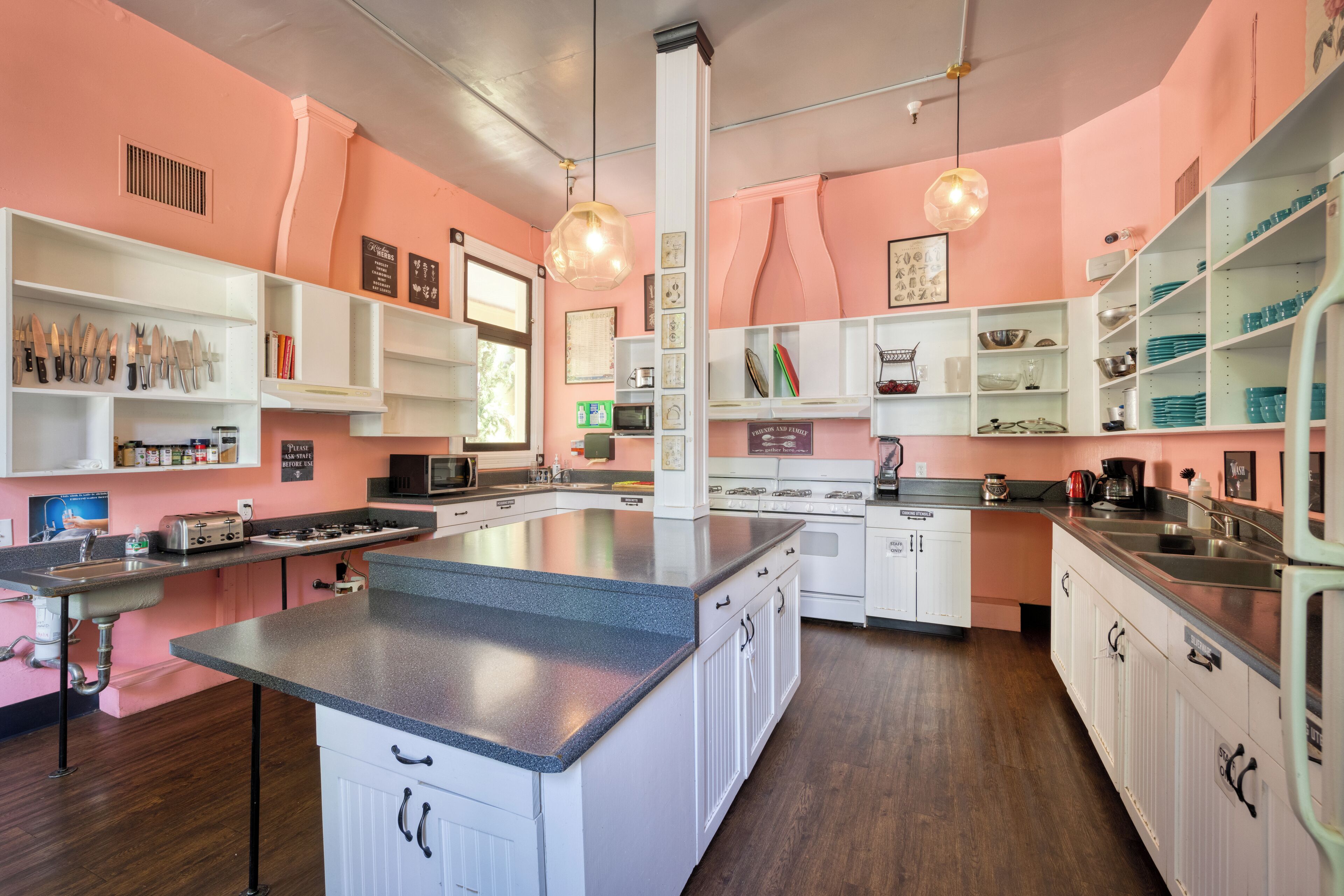 Cocina con armarios blancos, encimera de granito y una isla central. Hay luces colgantes, un microondas y una estufa.