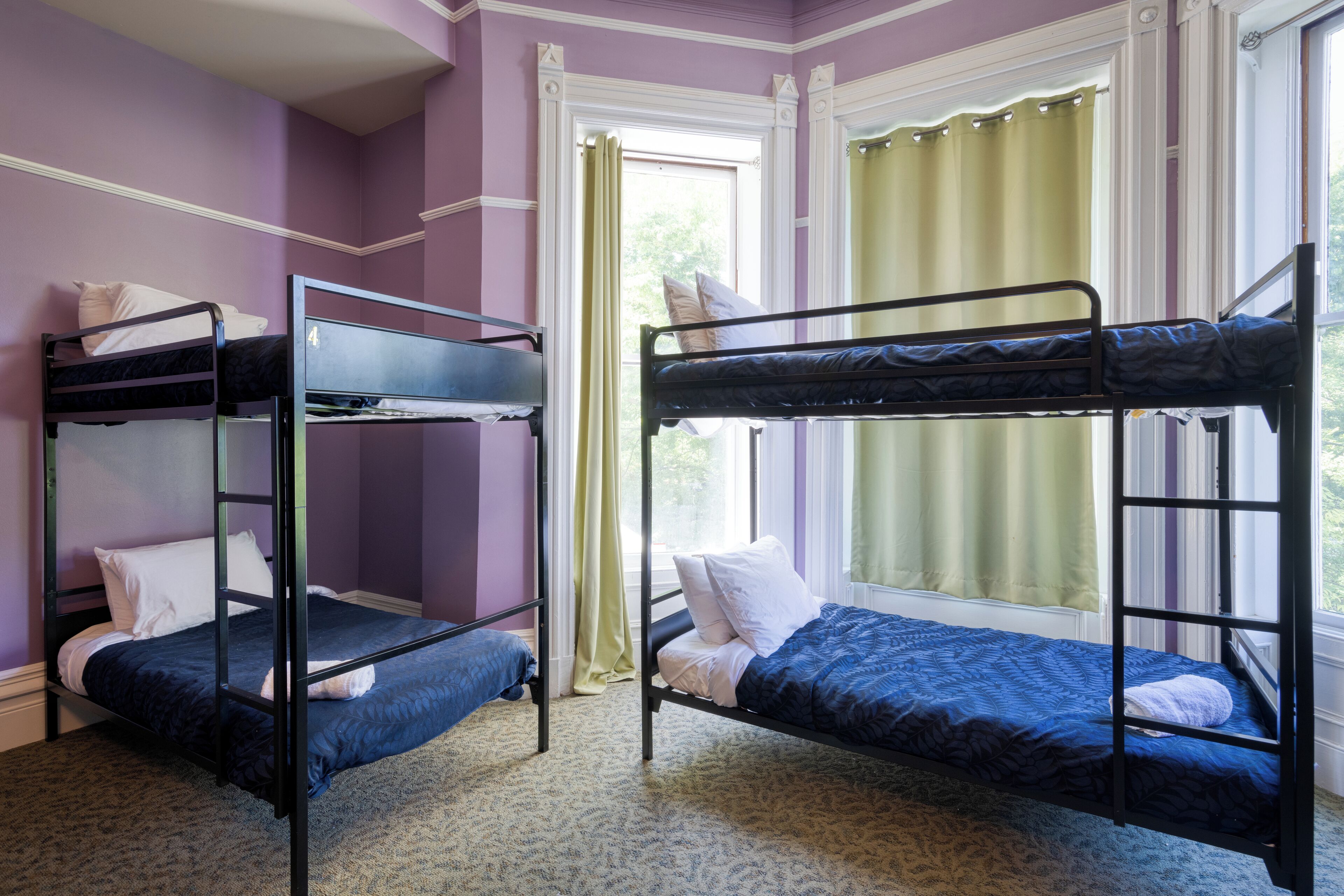 A room with two bunk beds, a window with curtains, and a carpeted floor.