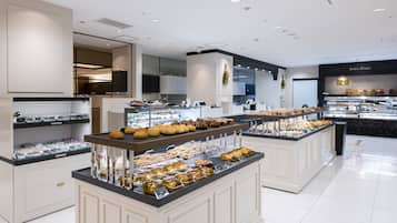 Une vitrine de boulangerie présentant diverses pâtisseries, avec un rayon de produits de charcuterie en arrière-plan.
