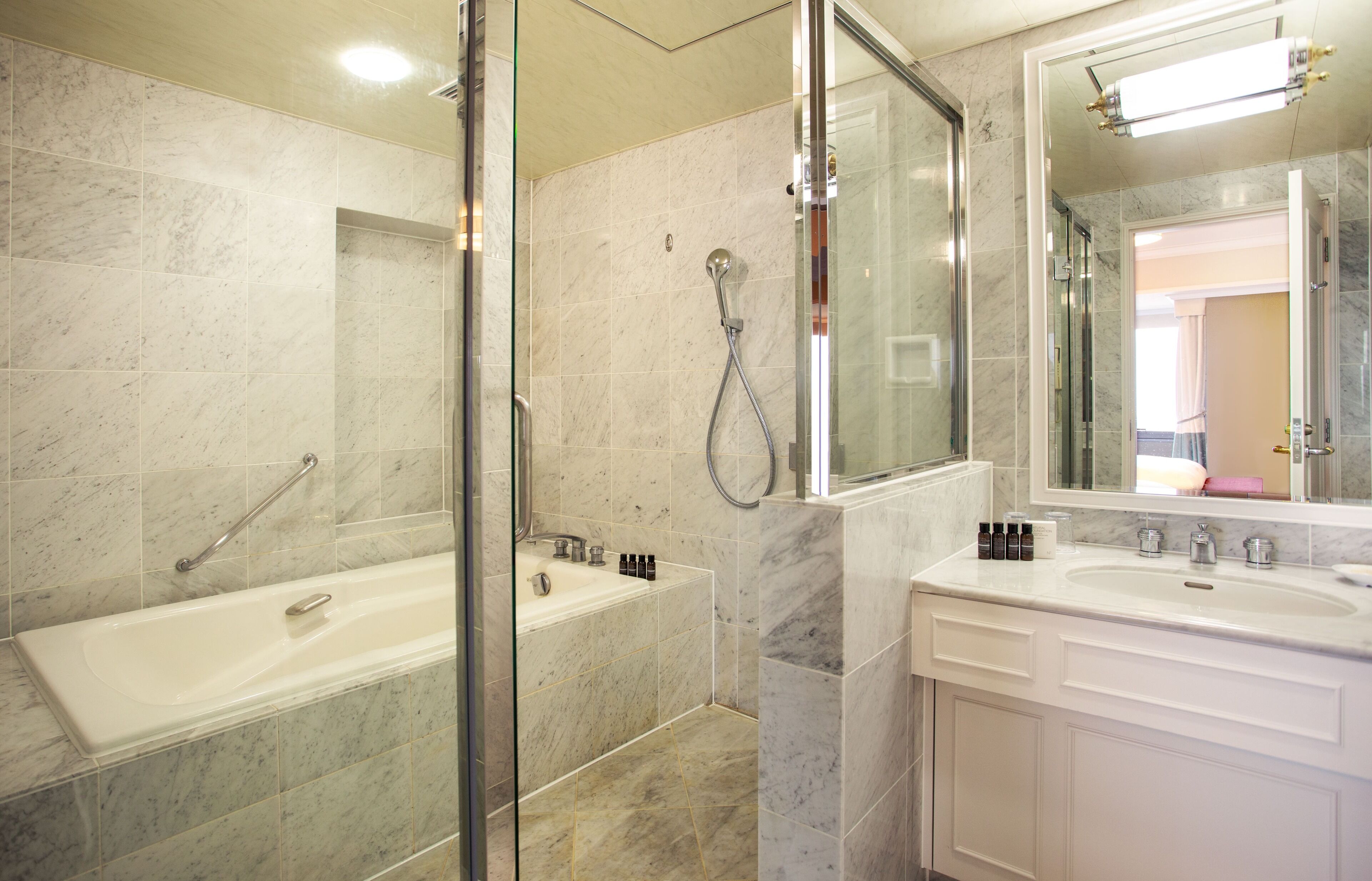 Ein modernes Badezimmer mit einer gläsernen Duschkabine, einer freistehenden Badewanne und einem Waschtisch mit großem Spiegel.
