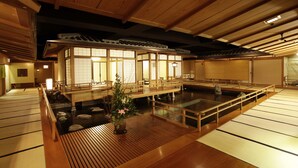 Een traditionele Japanse kamer met tatami vloerbedekking, een houten plafond en een vijver met koikarpers.