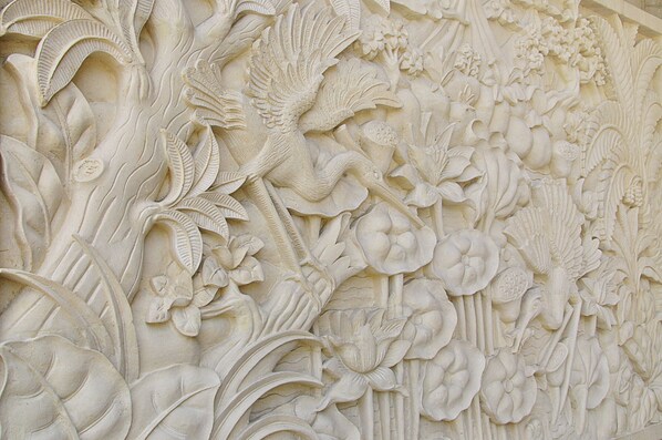 Pared tallada con detalle, adornada con motivos florales y de aves.