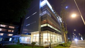 A modern building with multiple floors, large windows, and a well-lit exterior at night. - Cocor Spa Hotel (Neptun)