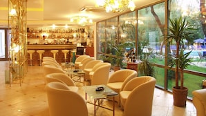 A bar area with a bartender, bar stools, and a variety of bottles. There are several chairs and tables arranged for seating. - Cocor Spa Hotel (Neptun)