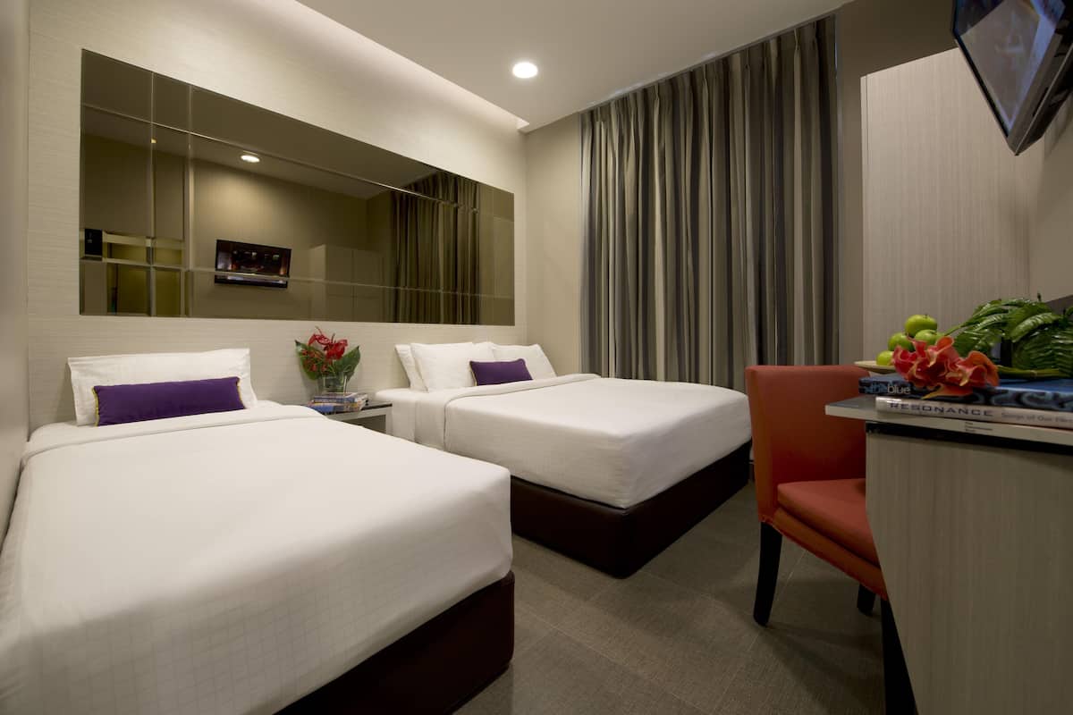 Une chambre d’hôtel avec deux lits, un bureau, une chaise, une télévision et un grand miroir.