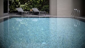 Ein Schwimmbecken mit Liegestühlen und einer Metallleiter.