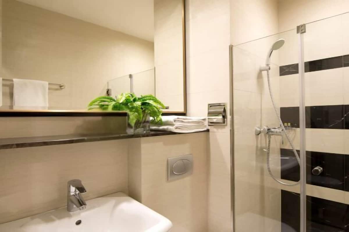 Une salle de bain moderne équipée d’un lavabo, d’un miroir, d’un porte-serviettes et d’une douche à parois de verre.