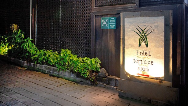 A hotel terrace sign with a green directional sign and a plant beside it. - Hotel Terrace at Kuta (Kuta)