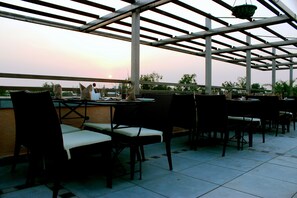 Un área de estar al aire libre con mesas y sillas, una estructura de pérgola y vistas al cielo.