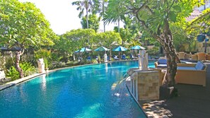 Una piscina al aire libre, sombrillas, sillones reclinables de piscina