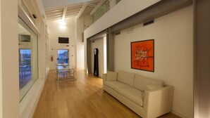 A modern interior with a wooden floor, a beige sofa, and a large window.