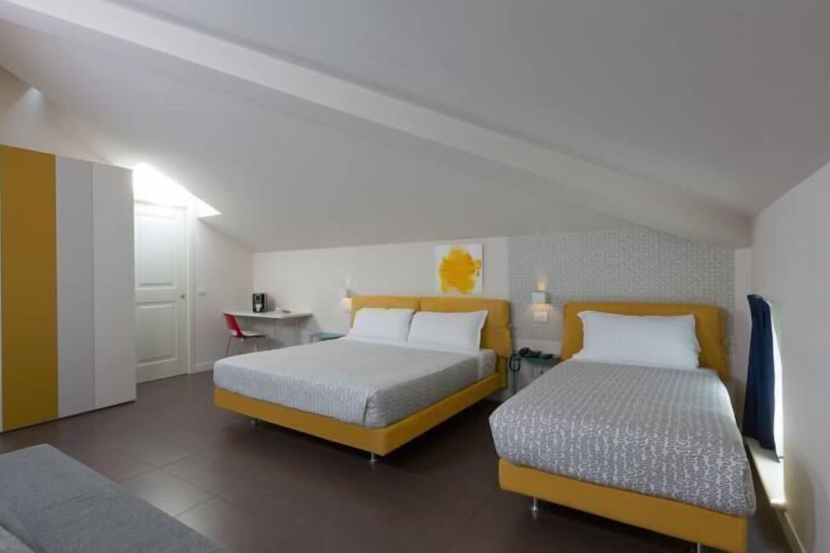 Ett hotellrum med två sängar, ett skrivbord och en soffa.